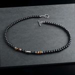 Collar elegante de ónix negro con 4 cuentas de ojo de tigre y cierre en acero inoxidable. Diseño unisex ideal para estilo diario o como regalo significativo.