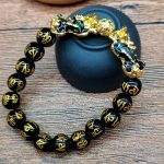 Lleva contigo un símbolo poderoso de abundancia y protección con esta elegante pulsera de cuentas de acrílico negro, complementada con un imponente Pixiu dorado con detalles azules iridiscentes. Su diseño moderno y llamativo combina la estética del Feng Shui con un estilo contemporáneo perfecto para uso diario