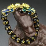 Lleva contigo un símbolo poderoso de abundancia y protección con esta elegante pulsera de cuentas de acrílico negro, complementada con un imponente Pixiu dorado con detalles azules iridiscentes. Su diseño moderno y llamativo combina la estética del Feng Shui con un estilo contemporáneo perfecto para uso diario