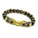 Lleva contigo un símbolo poderoso de abundancia y protección con esta elegante pulsera de cuentas de acrílico negro, complementada con un imponente Pixiu dorado con detalles azules iridiscentes. Su diseño moderno y llamativo combina la estética del Feng Shui con un estilo contemporáneo perfecto para uso diario