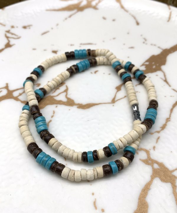 Añade un toque playero a tu look con nuestro collar surfista hecho a mano con cuentas de coco y cerámica. Perfecto para verano y espíritu libre.