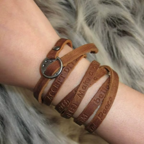 Nuestra pulsera larga de cuero envuelve tu muñeca con palabras que inspiran: Dream • Love • Believe • Peace • Imagine