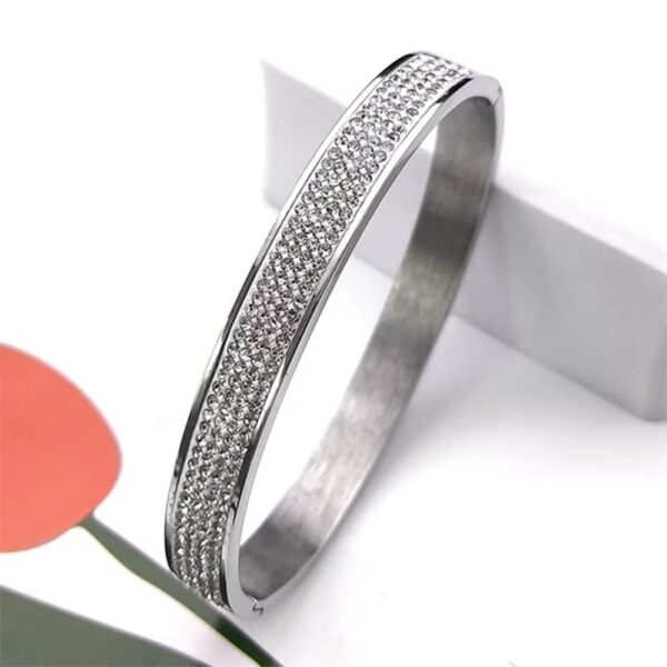 Inspirado en el lujo de la alta joyería, este brazalete combina la fuerza del acero inoxidable con un pavé de micro-cristales que capturan la luz desde cualquier ángulo, creando un efecto hipnótico que parece sacado de una constelación.